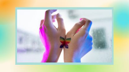 two hands with matching rainbow butterfly tattoo ideas held up against a window, with a colorful border