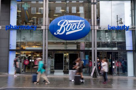 Shoppers and visitors out on Oxford Street pass Boots the chemist 