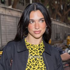 Dua Lipa attends the Monaco F1 Grand Prix wearing a yellow leopard print top from Coperni, the brand's boyfriend jean pants, and her Puma Speedcat OG sneakers