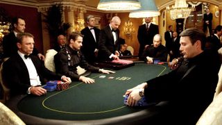 A still from Casino Royale, showing Bond, Le Chiffre, and others, sitting around a poker table