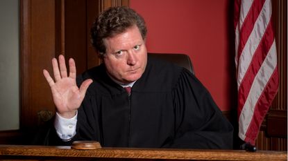 A judge holds up his hand in a "stop" gesture.