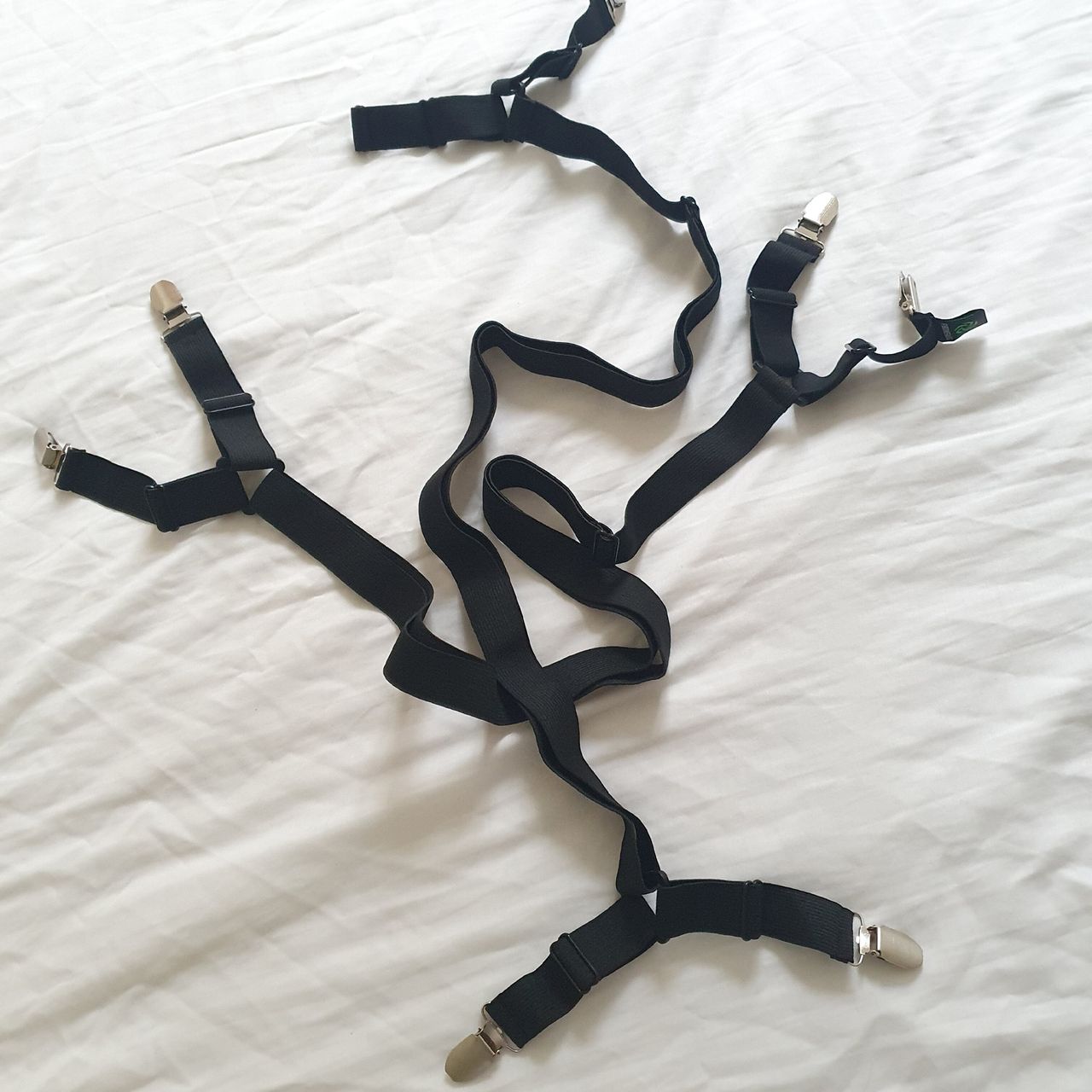 Black elasticated sheet straps being fitted to a white fitted sheet