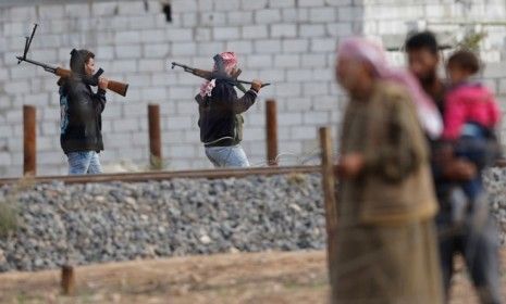 Machine-gun-toting fighters from the Free Syrian Army walk in the Syrian town of Ras al-Ain along the Turkish border.