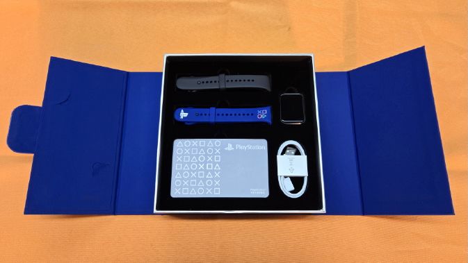 An open box showing a Xiaomi Smart Band 9, a PlayStation-branded blue band with the four controller logos, a second black band, a charging cable, and a PlayStation booklet.