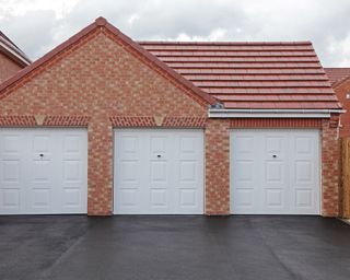 Garages and a tarmac driveway in front of a new house