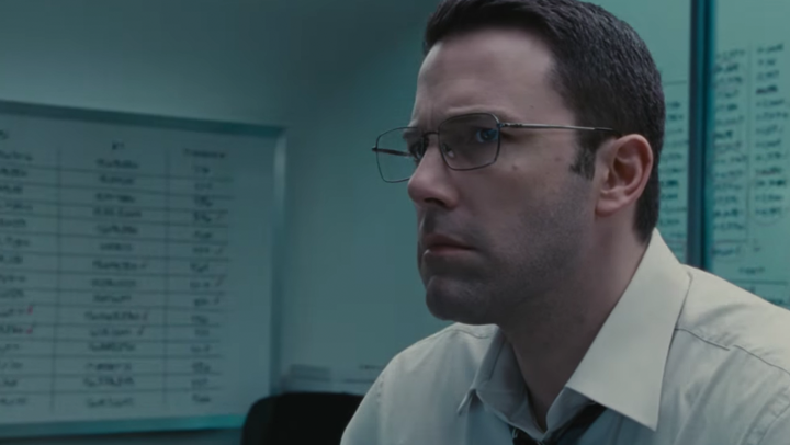 A still from the movie The Accountant in which Ben Affleck is wearing a white shirt and looking off camera.