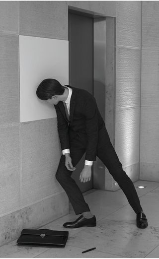 man in suit slumping against wall in resignation