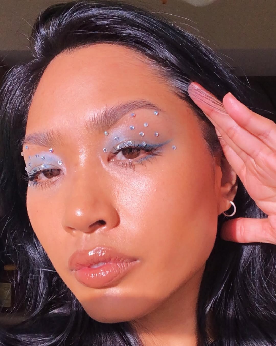 A woman with colorful eye makeup and gemstones.