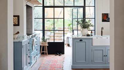 kitchen renovation rules, sky blue kitchen cabinets, view of garden via crittall doors, herringbone floor, basin in island, vintage rug