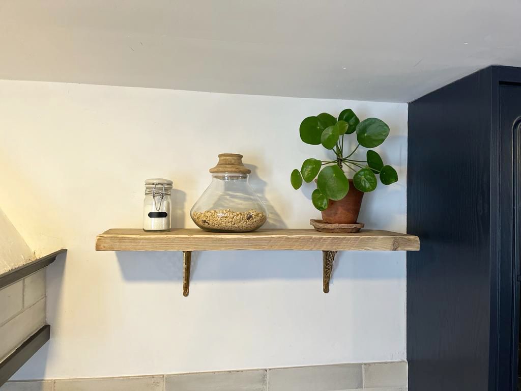 A wooden kitchen shelf with a plant, a jar and a kilner jar