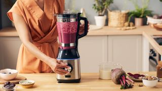 A blender filled with beetroots being run in a kitchen 
