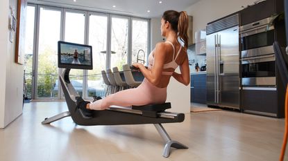 Woman rowing on Hydrow rowing machine in domestic setting