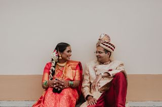 A couple in Indian wedding attire sitting on the floor