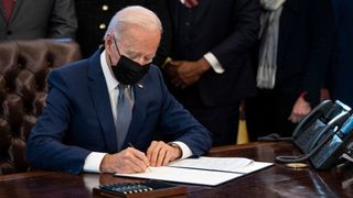 US president Joe Biden signing an executive order in the Oval Office