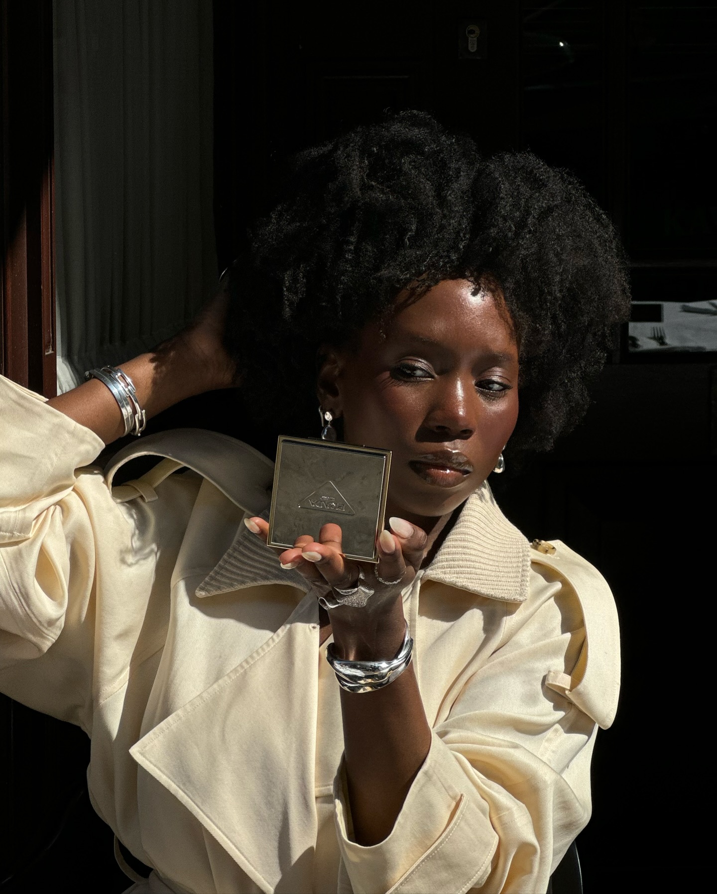 Danielle Jinadu wearing a butter yellow trench coat and defined 4c curls in London.