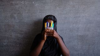 Girl holding up pens in front of her face