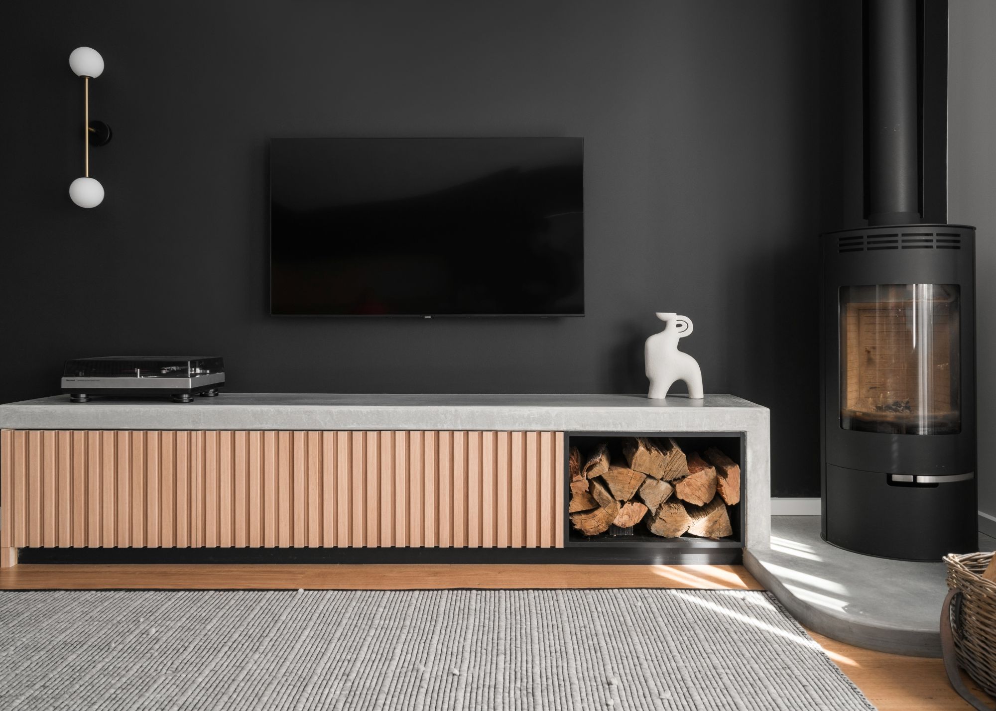 A living room with a black painted wall, a wooden tv fireplace unit, and a TV above it