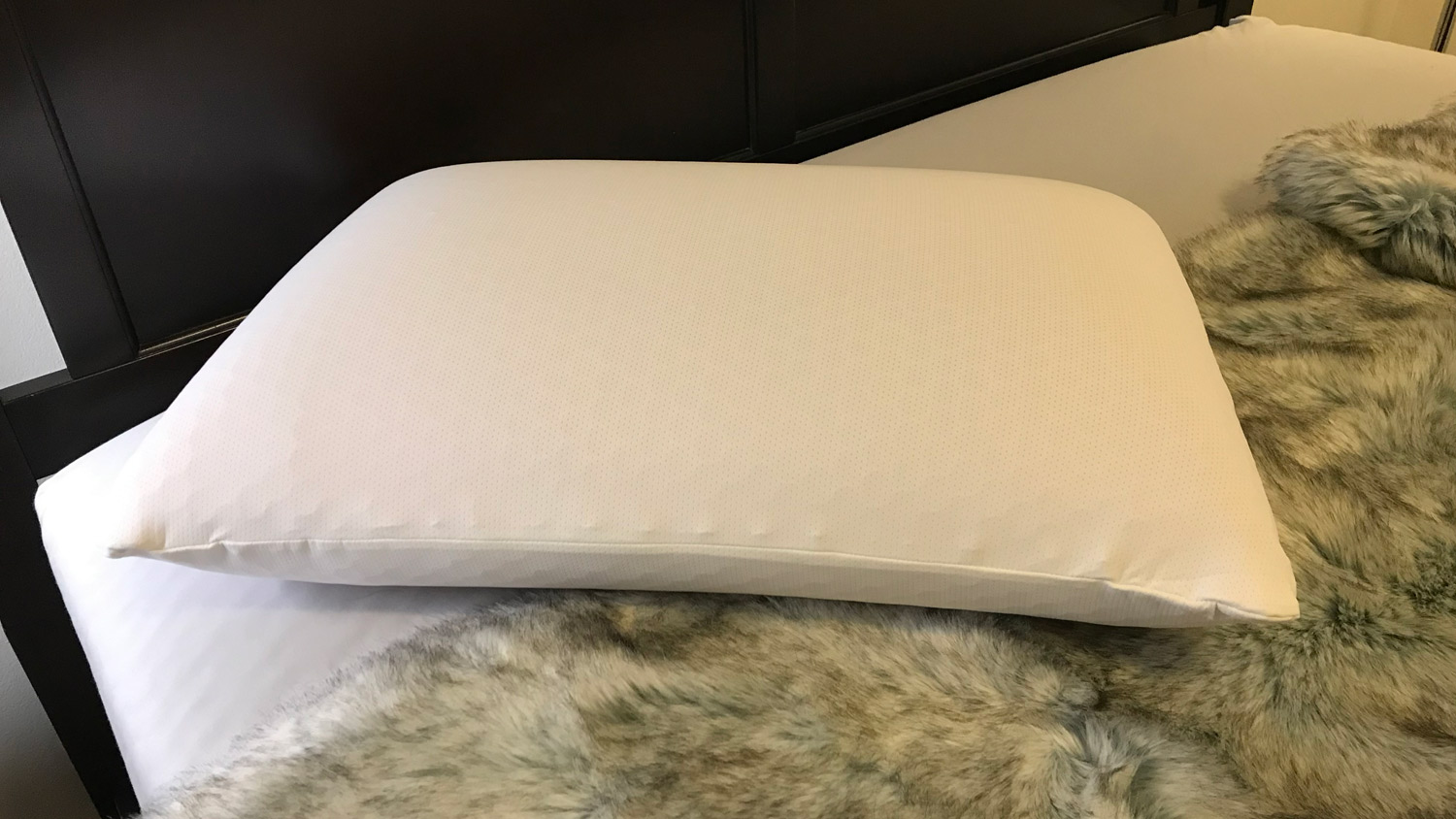O Purple Harmony Pillow em uma cama ao lado de um edredom de pele sintética