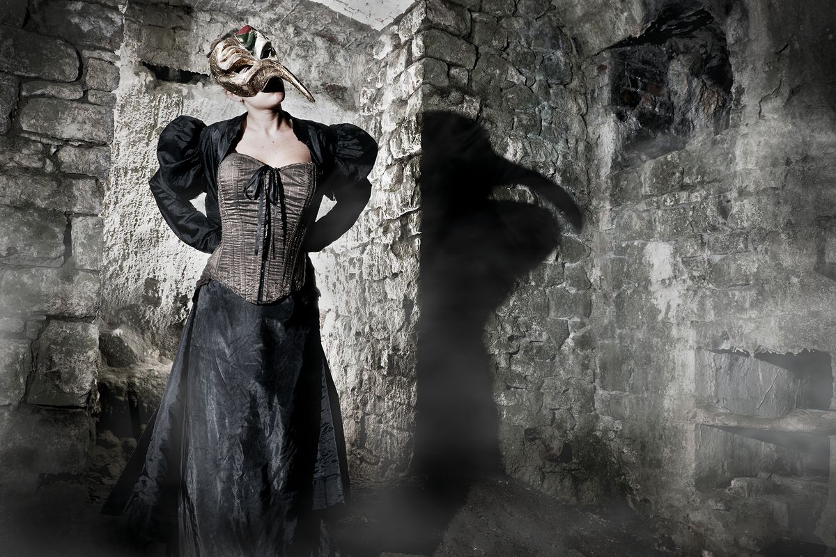 Woman wearing plague mask, in a cellar, with dramatic lighting