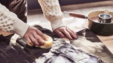 A person showing how to rewax a Barbour jacket