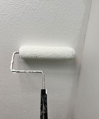 Painting a ceiling white using a roller on an extension pole