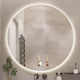Round lighted vanity mirror hanging on bathroom wall