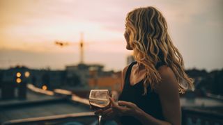 Woman holding a wine glass standing on a rooftop