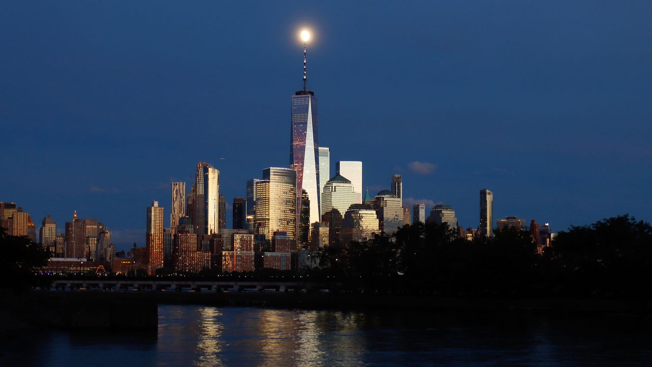 A 92% illuminated waxing gibbous moon rises above lower Manhattan and One World Trade Center ahead of the Full Sturgeon Moon and Blue Moon in New York City on Aug. 19, 2021 as seen from Jersey City, New Jersey.