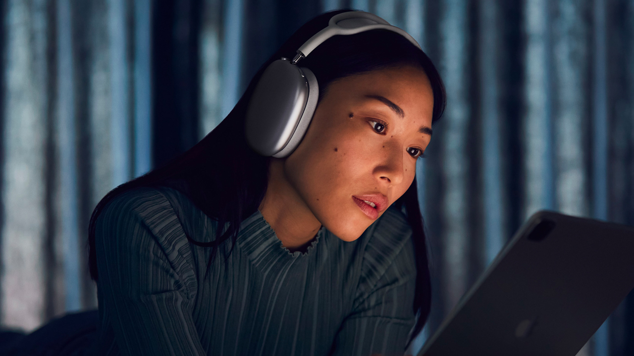 Женщина в наушники Apple Airpods Max в темной комнате, глядя на экран