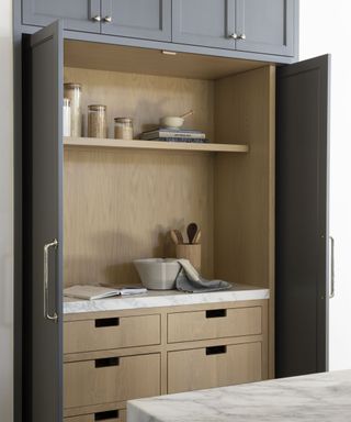 baking cupboard with pale wood doors and marble countetop