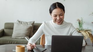 Smiling woman using a laptop and one of the best free blogging platforms.