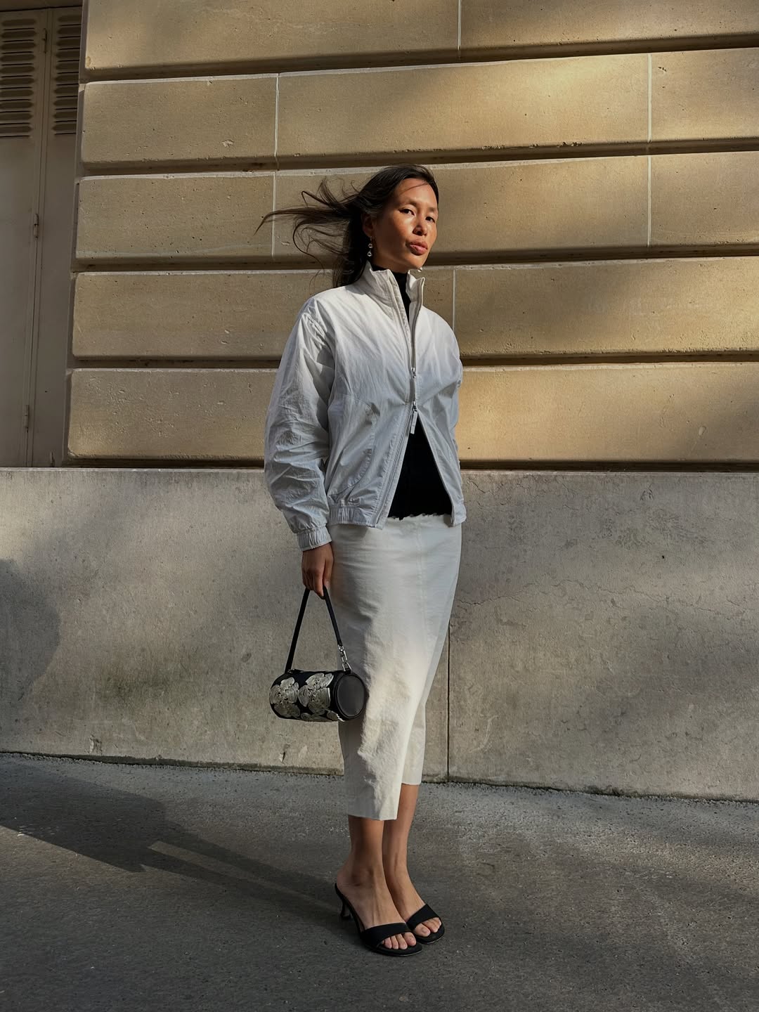 Viki in a white pencil skirt and windbreaker