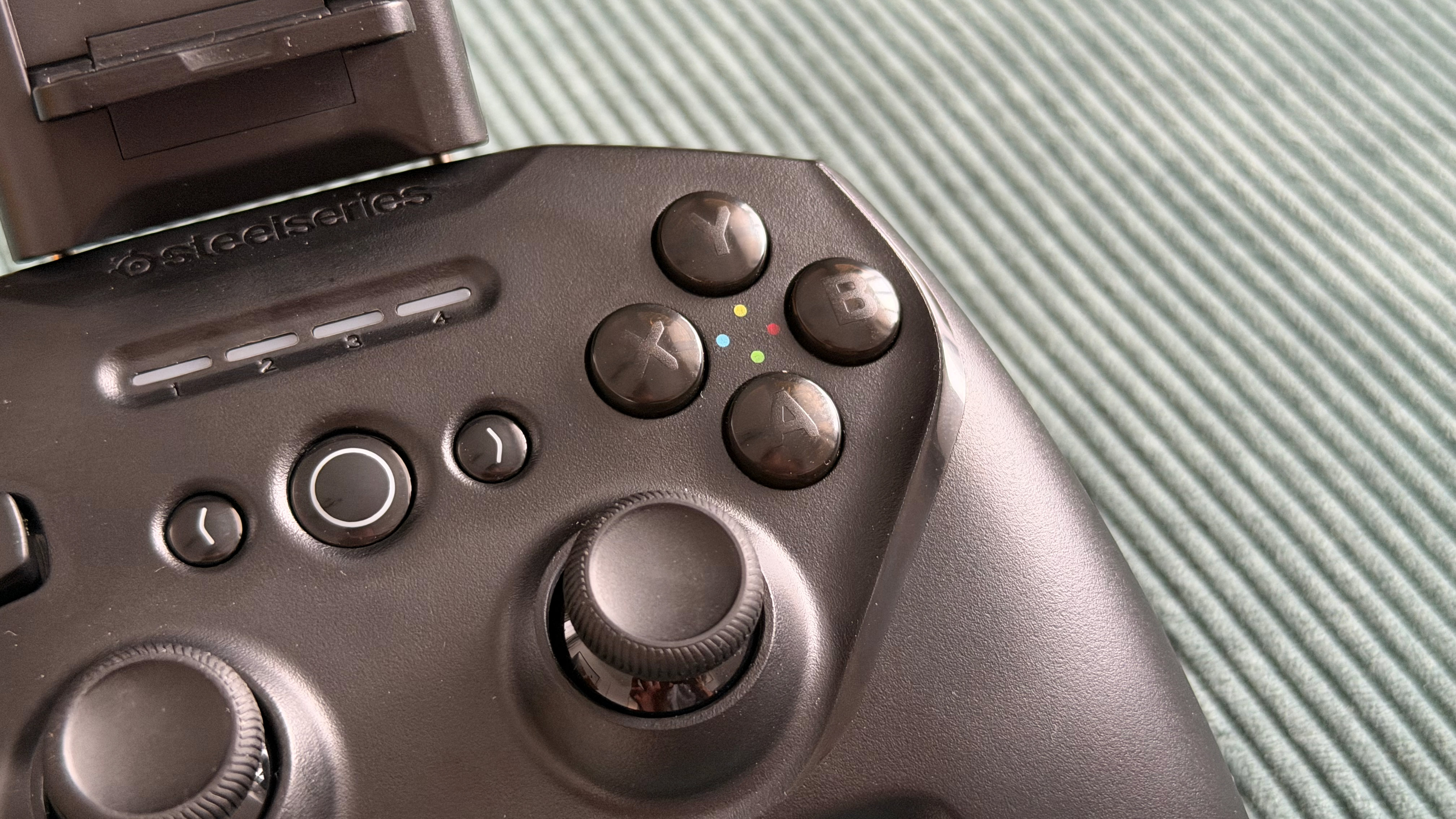 The SteelSeries Stratus+ mobile and PC controller on top of a green carpet surface