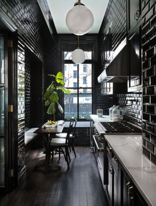 A small, galley kitchen with black tiles