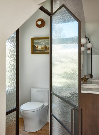 A water closet in a bathroom with frosted glass