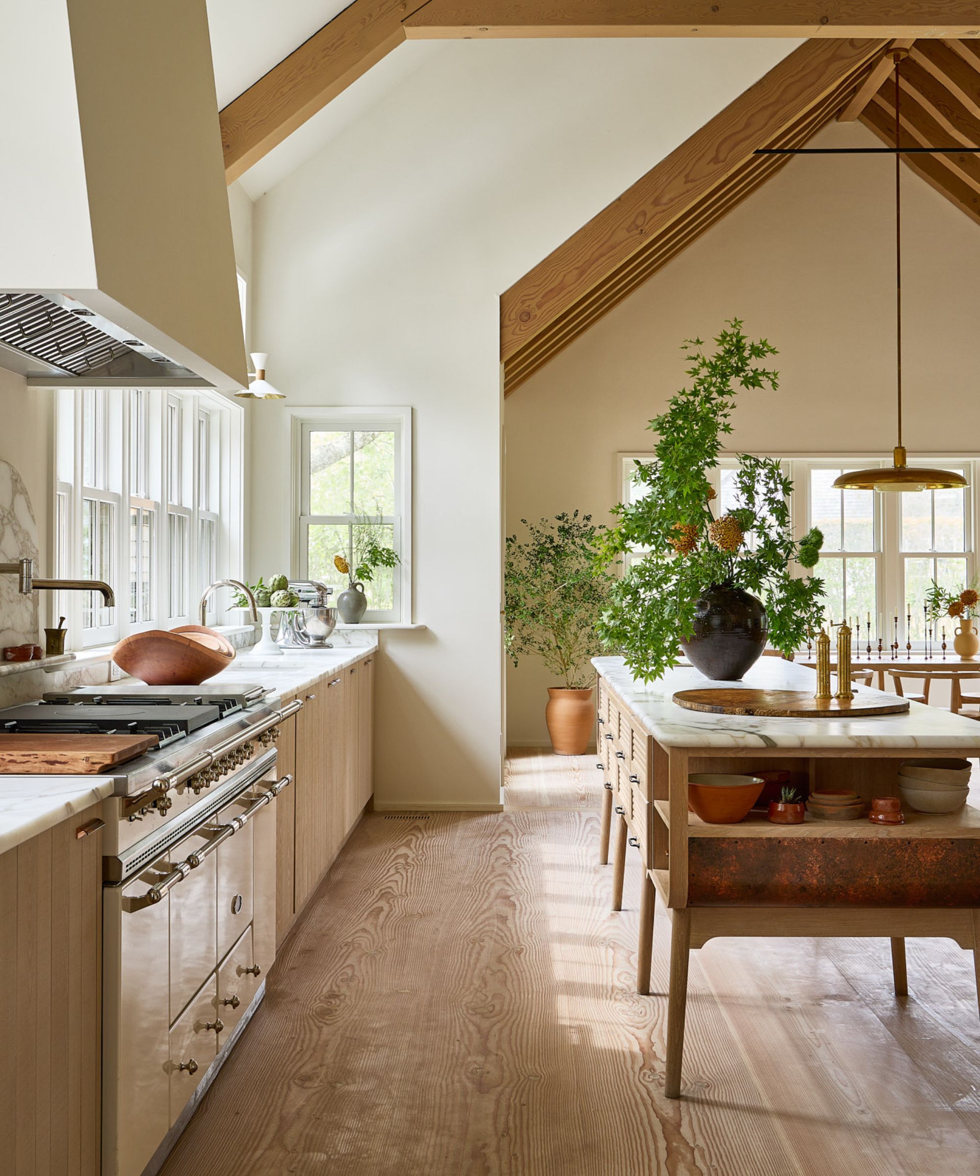 A coastal scandinavian kitchen with wooden cabinets, marble countertops, and warm white walls