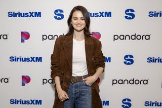 Selena Gomez wearing jeans, a white crewneck t-shirt, and a brown suede belt.