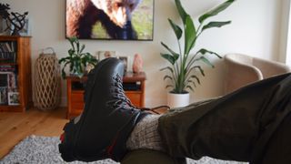 how to break in hiking boots: man watching tv with hiking boots on