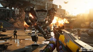 Artwork for the Avatar: Frontiers of Pandora video game. This is a first-person view of someone who is holding a large yellow and gray rifle with blue hands wearing lots of bracelets and beads. They are firing at a large mech directly in front of them, who also has a giant gun. In the background you can see a military compound with several camo-wearing soldiers running towards you.