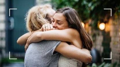 Woman smiling as she hugs friend at outdoor barbecue with fairy lights, enjoying the benefits of not drinking alcohol