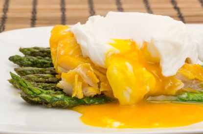 smoked haddock on a plate with a poached egg and yolk, and asparagus