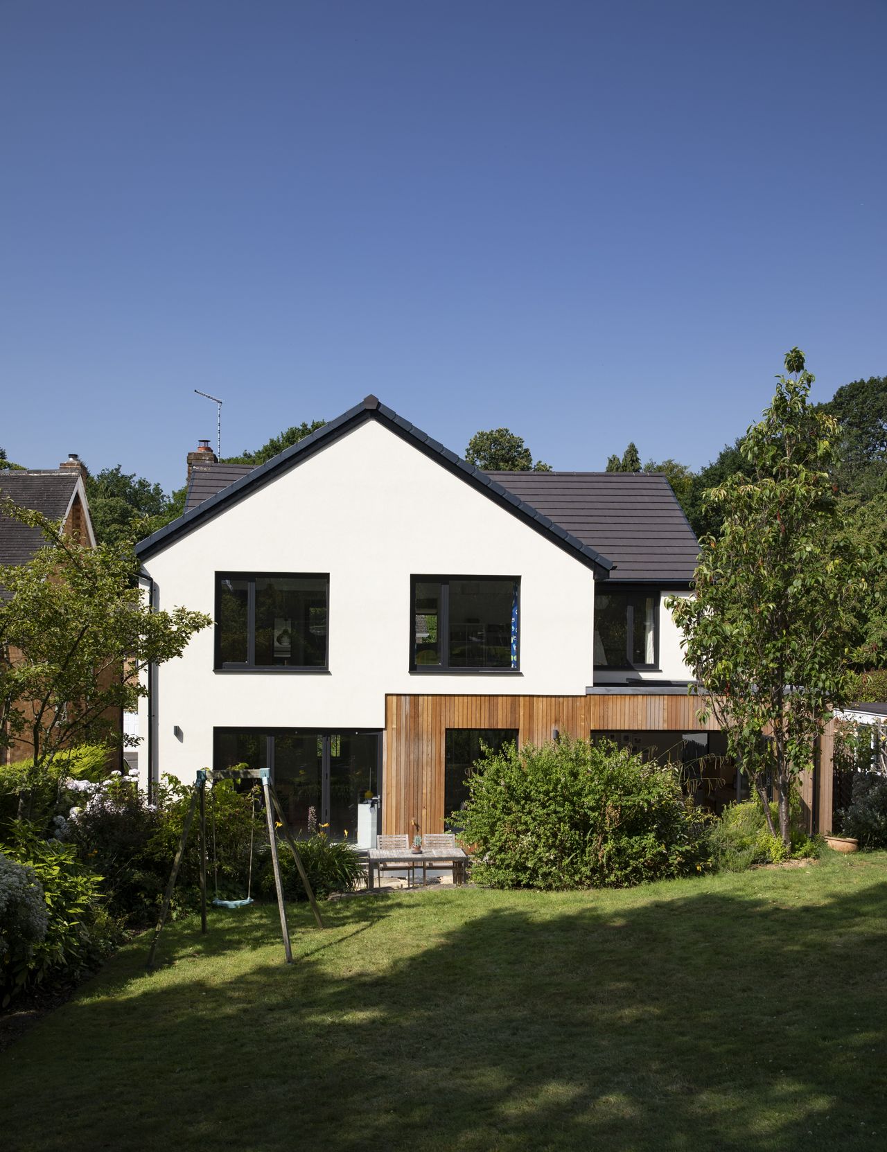 The cedar-clad kitchen extension links the house to the north-facing garden, drawing light through the flat roof with a Velux window.