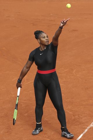Serena Williams serves a tennis ball at the 2018 French Open while wearing a custom Nike compression catsuit