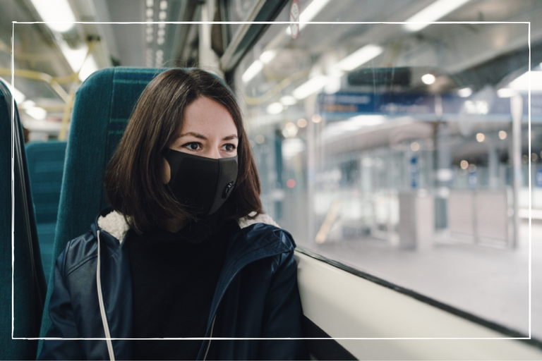 a close up of a woman following new face mask rules and wearing a mask on the train