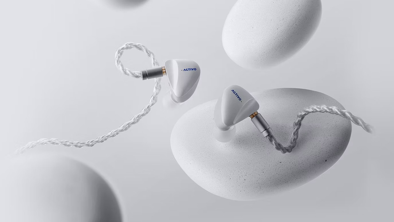 Activo Scoop earbuds on a light great background with what looks like grey pebbles