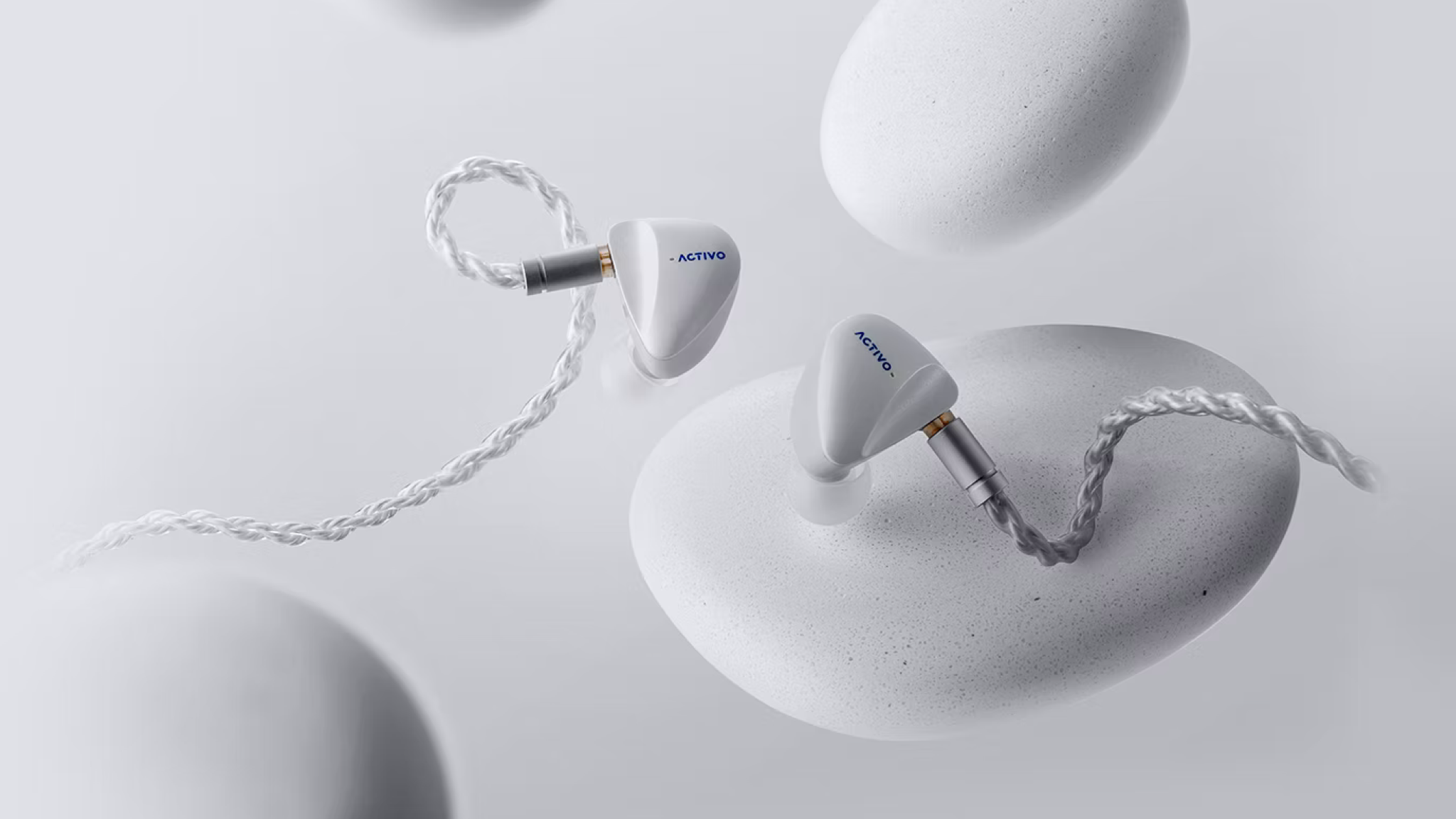 Activo Scoop earbuds on a light great background with what looks like grey pebbles