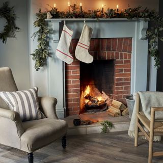 armchairs around a lit fire with stockings hanging near