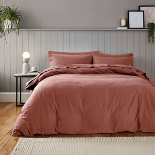 A bed covered in a terracotta brushed cotton duvet cover