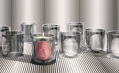 One lit Diptyque candle amongst other black and white holders
