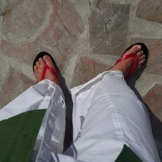 Woman wears white trousers, red sandals